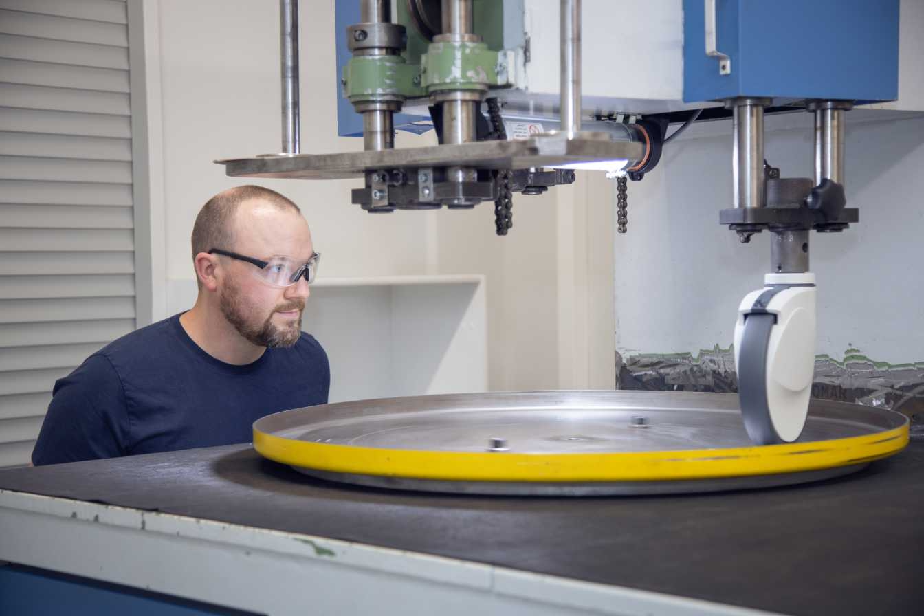 Man looks at a castor that has to cross a threshold several times with the help of a machine 